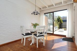 uma sala de jantar branca com uma mesa e cadeiras em Holiday home het Zeepaardje em Noordwijkerhout