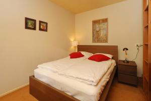 Schlafzimmer mit einem Bett mit weißer Bettwäsche und roten Kissen in der Unterkunft Holiday home Zeelust in Noordwijkerhout