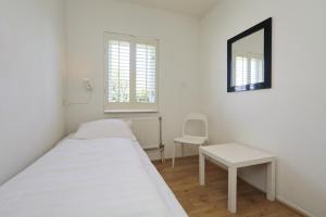 ein weißes Zimmer mit einem Bett, einem Tisch und einem Spiegel in der Unterkunft Holiday home de Zeester in Noordwijkerhout