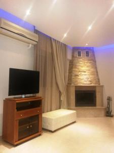 a living room with a television and a fireplace at Villa Olive Grove in Afantou
