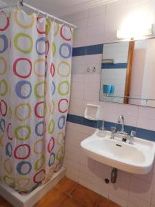 a bathroom with a sink and a shower curtain at Perdika Mare Guesthouse in Perdika