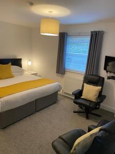 a bedroom with a bed and a chair and a window at Tirah Guest House in Aldeburgh