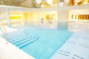 Une grande piscine avec des escaliers se trouve dans un bâtiment. dans l'établissement Hotel Neptun - Terme & Wellness Lifeclass, à Portorož