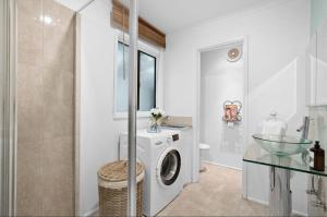 a bathroom with a washing machine and a glass table at Stylish 2-Bed Home, Stunning View, Fire Pit, Festoon Lights, BBQ and walk to Pub in Poowong +12 photos