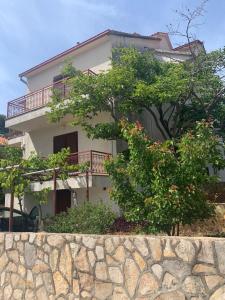 a white house with a tree in front of it at APARTMENTS Vuković in Vrboska