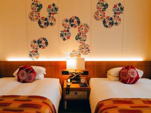 two beds in a hotel room with flowers on the wall at Miyakojima Tokyu Hotel & Resorts in Miyako-jima