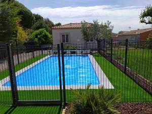 a fence with a swimming pool in a yard at Le Logis de Liliana in Villemoustaussou
