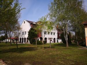 a large white house with trees in the yard at Laguna Panzió in Gárdony