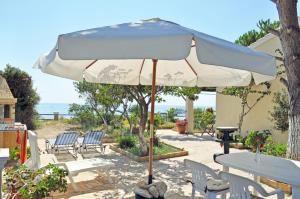 a white umbrella sitting on top of a patio at Corfu Beachfront holiday Houses Yannis on Agios Gordios beach in Agios Gordios +21 photos