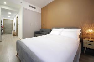 a bedroom with a large white bed and a chair at Signature Holiday Homes - Stunning Furnished Studio Apartment in JVC in Dubai