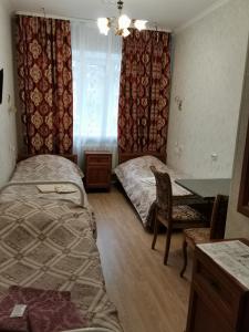 1 dormitorio con 2 camas, mesa y ventana en Harmony, en Cherepovets