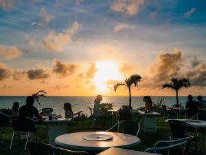 people sitting at tables on the beach watching the sunset at Miyakojima Tokyu Hotel & Resorts in Miyako-jima