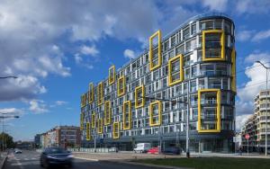 ein hohes Gebäude mit gelben Fenstern auf einer Straße in der Unterkunft Apartments Harfa in Prag