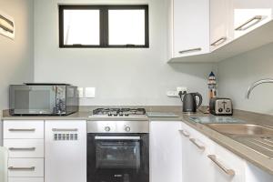 a white kitchen with a stove and a sink at Sea De La Vie 25 by HostAgents in La Mercy