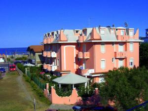 a large pink building with an umbrella in front of it at Appartamenti Doria II in Porto Garibaldi