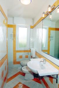 a bathroom with a sink and a toilet and a mirror at Appartamenti Doria II in Porto Garibaldi