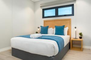 een slaapkamer met een groot bed met blauwe kussens bij 16 on Bree Luxury Apartments in Kaapstad