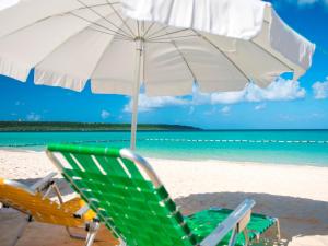 a green and white umbrella and chairs on a beach at Miyakojima Tokyu Hotel & Resorts in Miyako-jima