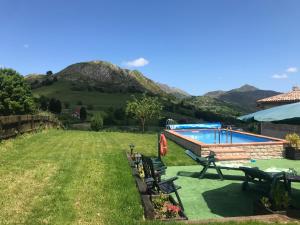 un patio con una piscina con montañas al fondo en EL HOGARIN DE ARRIONDAS, en Arriondas