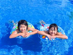 two boys are riding on inflatables in a swimming pool at Miyakojima Tokyu Hotel & Resorts in Miyako-jima