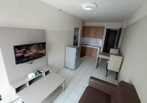 Il comprend une petite cuisine avec un canapé et une télévision. dans l'établissement X-pressbedroom Mutiara-Bekasi, à Bekasi