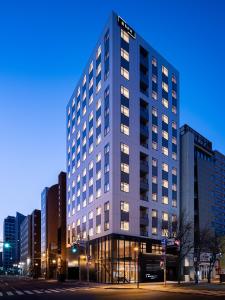 a tall building with windows on a city street at Bespoke Hotel Sapporo in Sapporo