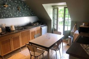 een keuken met een tafel en stoelen in een kamer bij L’annexe du Manoir in Gauciel