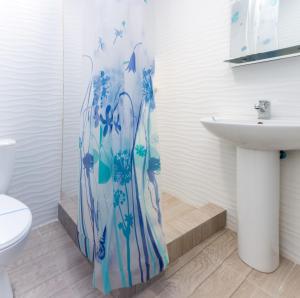 a bathroom with a blue shower curtain next to a sink at Zenith Hotel in Odesa +30 photos