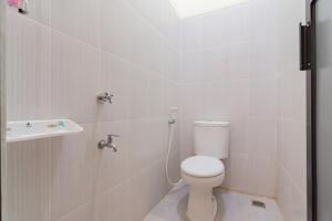 a white bathroom with a toilet and a sink at RedDoorz near Arka Sepinggan Airport Balikpapan in Balikpapan +14 photos
