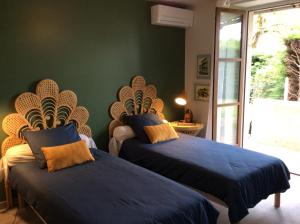 - 2 lits dans une chambre dotée d'un mur vert dans l'établissement Le Cottage des Mésanges, à Villefranche-de-Rouergue