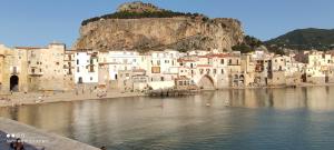 a group of buildings on a beach next to a body of water at Duomo Rooms Cefalù in Cefalù