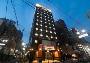 a tall building with a hotel sign in a city at APA Hotel Namba Shinsaibashi Nishi in Osaka