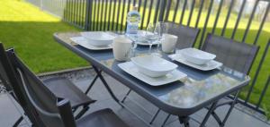 - une table avec des assiettes, des verres et une bouteille d'eau dans l'établissement VOJCAR Apartments, à Rewal