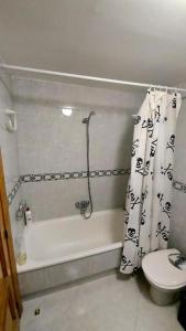 y baño con aseo y cortina de ducha. en Room in an apartment en Granada