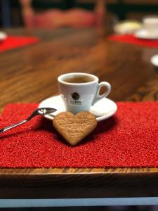 a cup of coffee and a heart shaped cookie on a red napkin at Chata pod Obřím hradem in Nicov