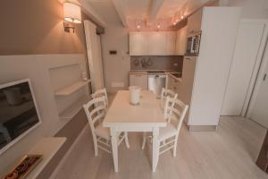 una piccola cucina con tavolo e sedie bianchi di BILOCALE BELLA VISTA a Temù