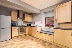 a kitchen with wooden cabinets and a white refrigerator at Elliot Suite No3 - Donnini Apartments in Ayr