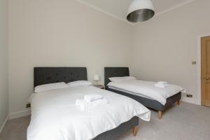 two beds in a room with white sheets and towels at Stylish Beach Pad on Scotland's Golf Coast in North Berwick