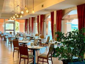 - une salle à manger avec des tables, des chaises et des fenêtres dans l'établissement Villa Susanna Degli Ulivi - Resort & Spa, à Colonnella