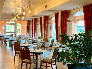 una sala da pranzo con tavoli, sedie e finestre di Villa Susanna Degli Ulivi - Resort & Spa a Colonnella