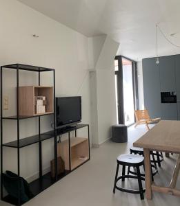 ein Wohnzimmer mit einem TV und einem Tisch in der Unterkunft Huyze Cordoeanier in Brügge