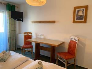 een kamer met een tafel, 2 stoelen en een bed bij Zur Linde in Traitsching