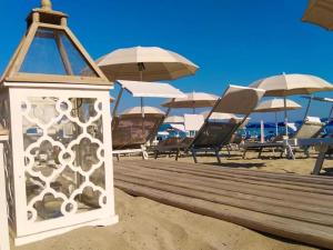 a light on a beach with chairs and umbrellas at Piccadilly Rooms Restaurant and Beach in Santa Maria al Bagno