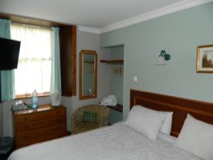 a bedroom with a bed and a chair and a window at Sunnyside House in Rothesay