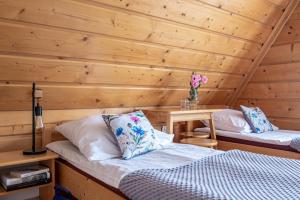 twee bedden in een kamer met een houten muur bij Pawlikówka 2 in Zakopane