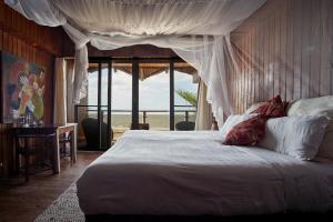 ein Schlafzimmer mit einem weißen Bett mit Baldachin in der Unterkunft Catembe Gallery Hotel in Maputo