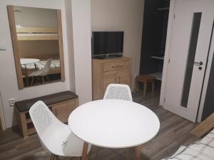 a white table and chairs in a room with a television at Penzion-Cukroška in Hlušovice