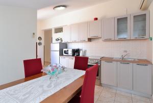 eine Küche mit weißen Schränken und einem Tisch mit roten Stühlen in der Unterkunft Apartment Andela 250 in Fažana