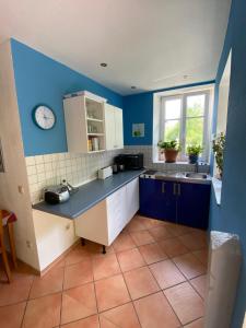 una cocina con paredes azules y un reloj en la pared en Ferienwohnung Südliche Weinstraße zwischen Wald und Reben en Klingenmünster