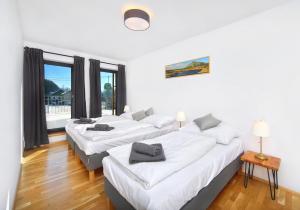 3 łóżka w pokoju z białymi ścianami i drewnianą podłogą w obiekcie Podstata Apartments Vrchlabí - Rotterovka w Vrchlabi